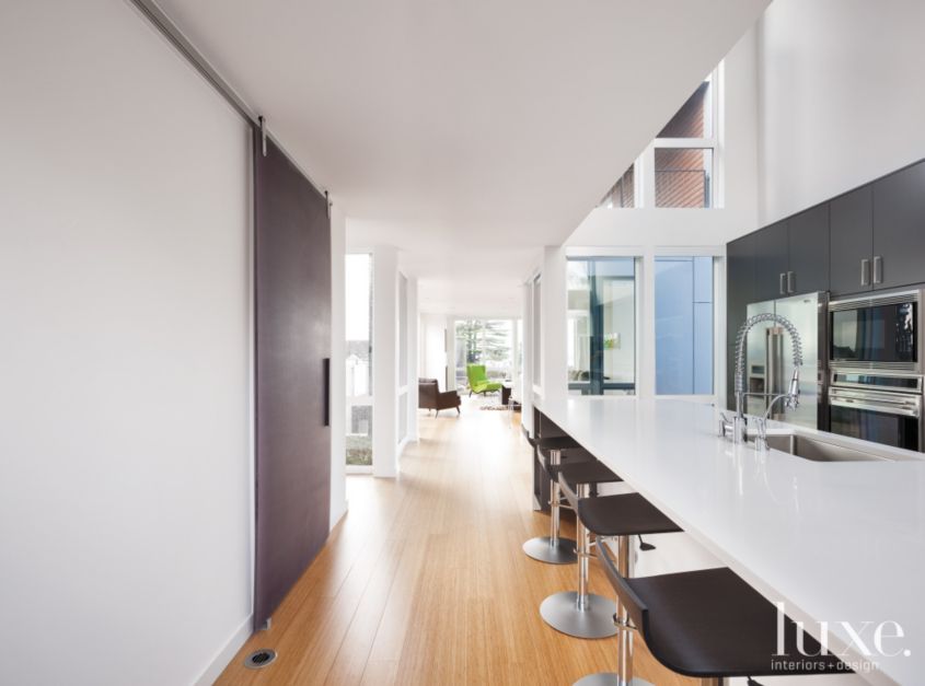 modern barn door used for pantry in sleek white kitchen with black accents