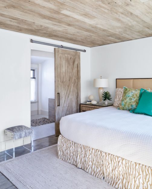 white washed wood barn door on tracks in neutral primary bedroom