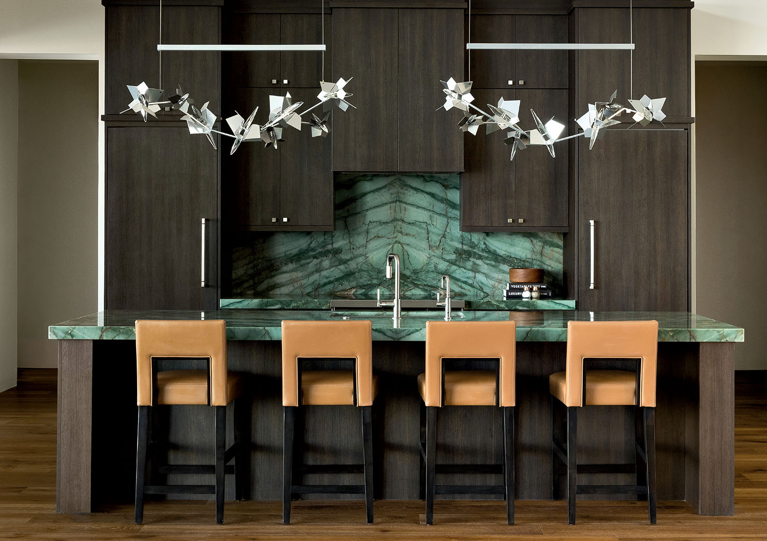 A modern kitchen featuring a green marble countertop and stylish chairs.