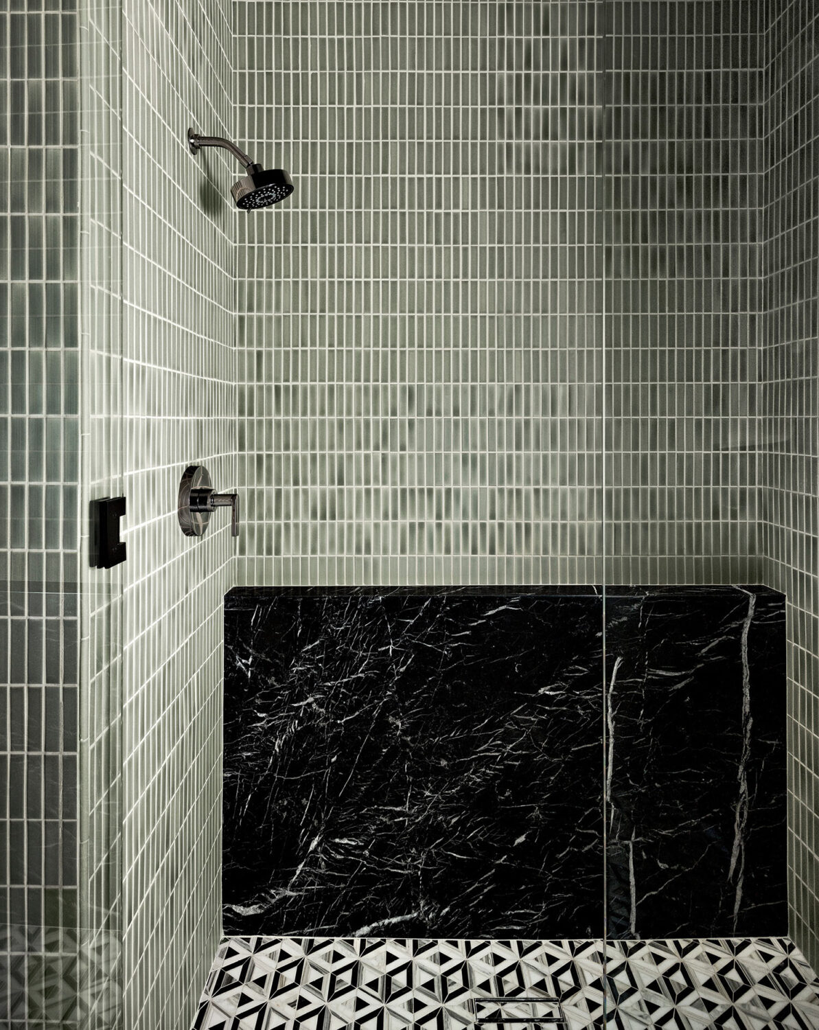Stylish bathroom with contrasting black and white tile flooring and a contemporary glass shower.