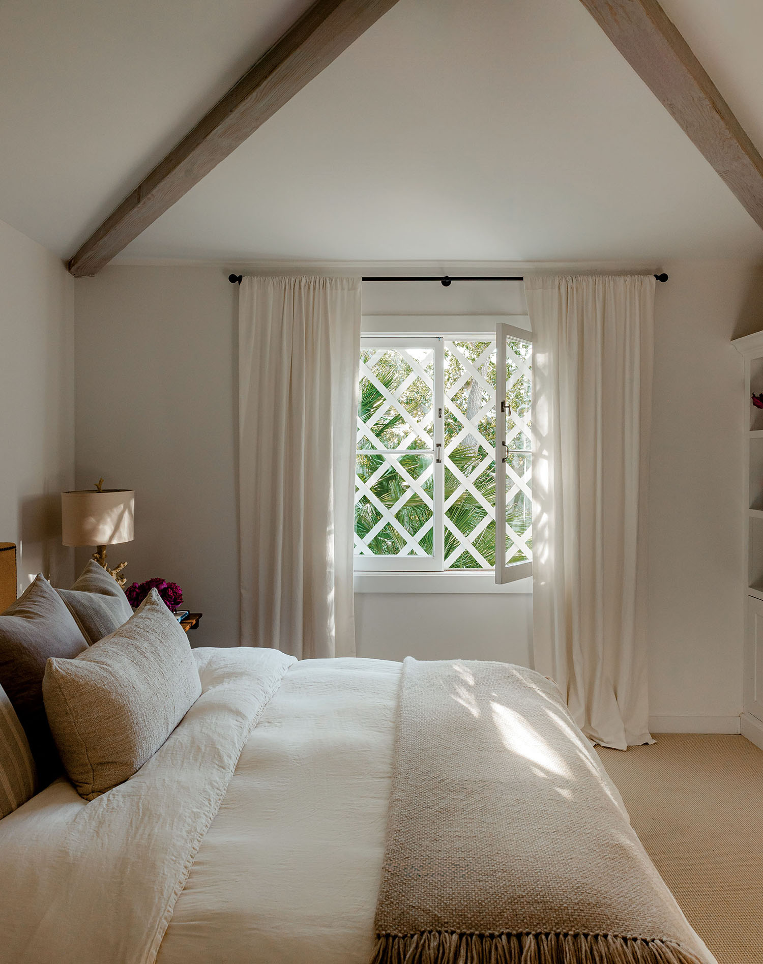 A cozy bedroom featuring a neatly made bed and a large window letting in natural light.