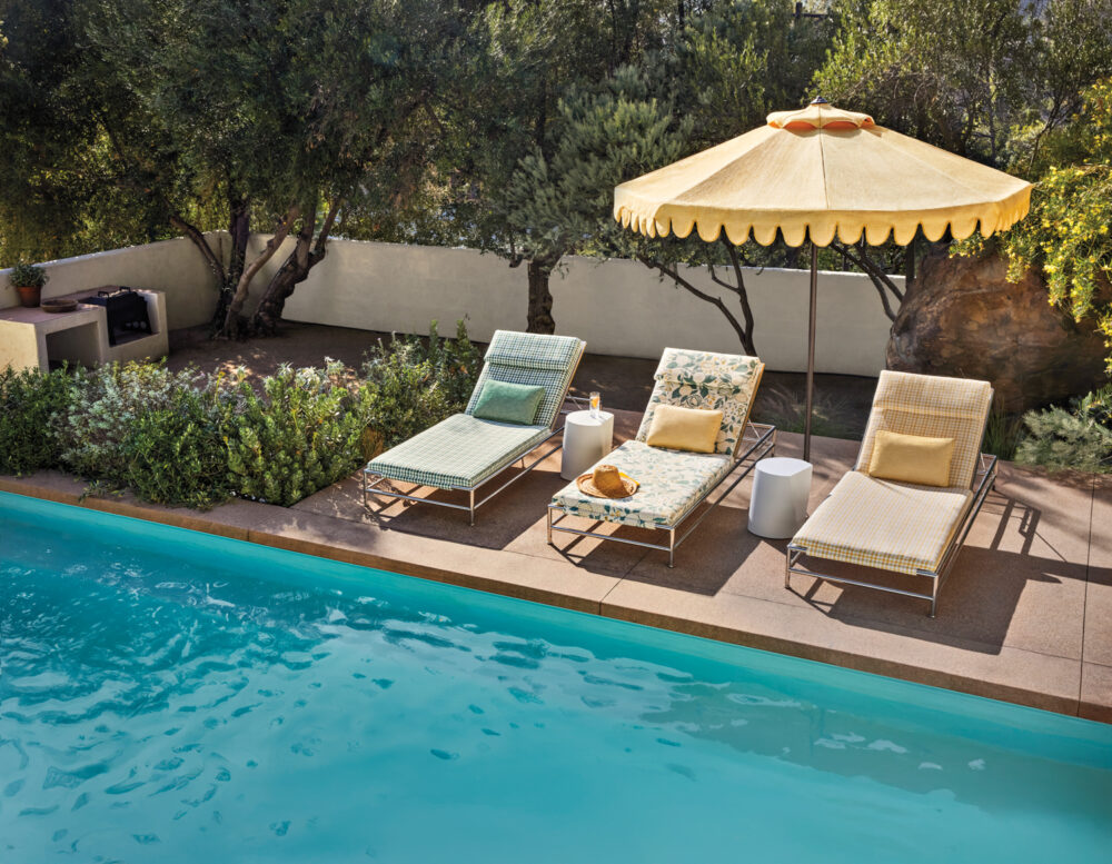 A serene pool scene with a vibrant yellow umbrella positioned at the edge.