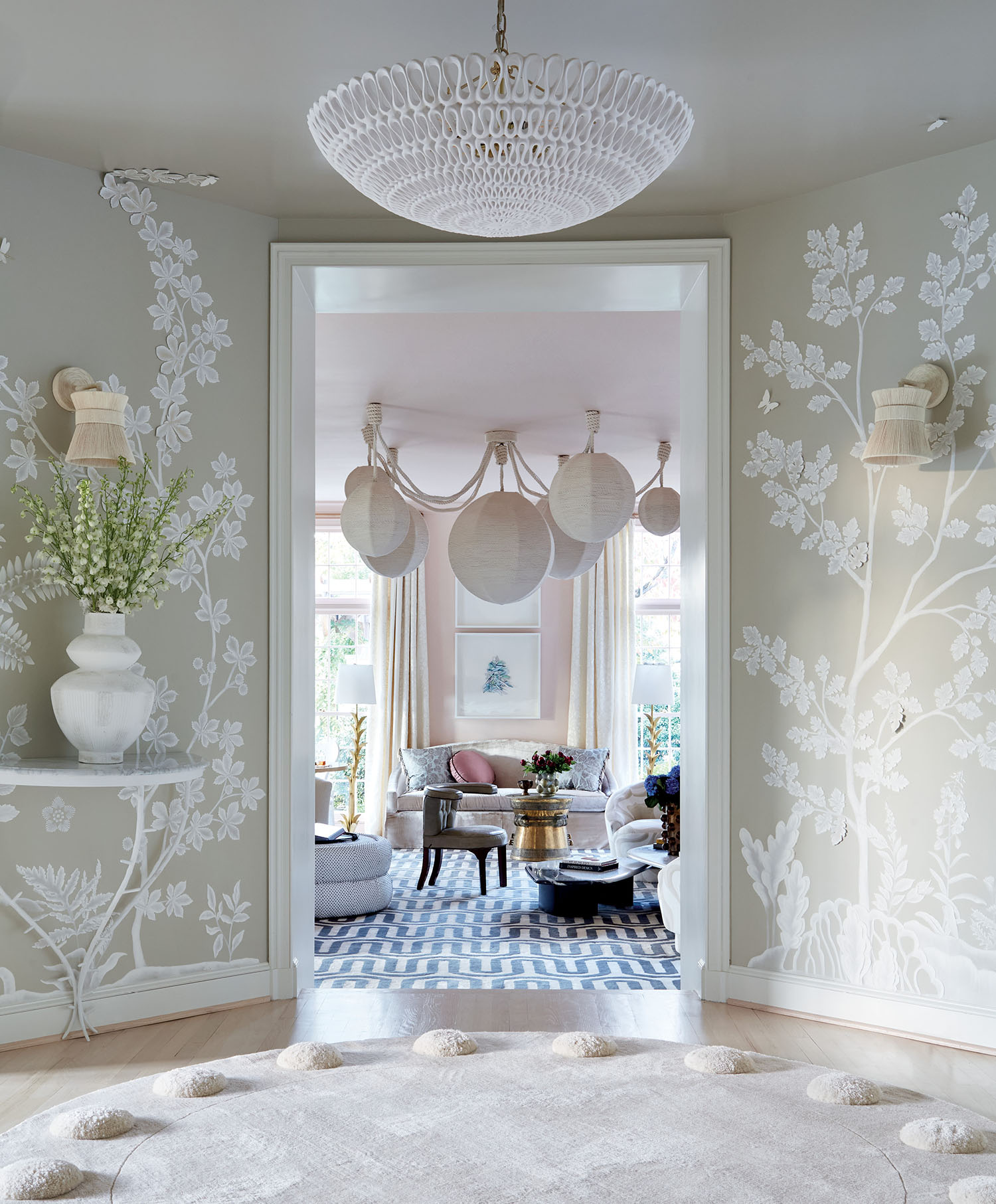 A spacious entry room featuring a large rug and an elegant chandelier hanging from the ceiling.