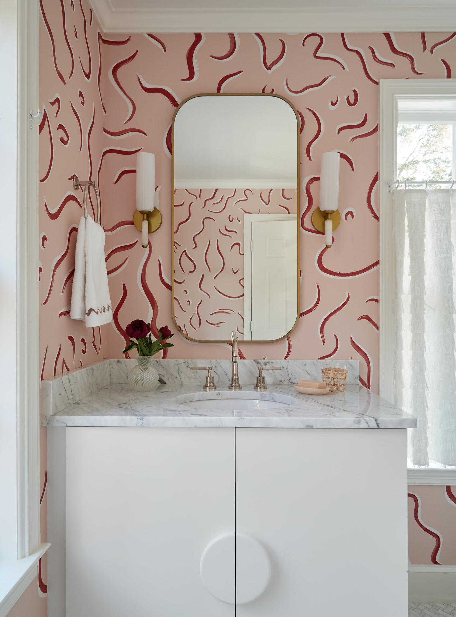 A bathroom featuring pink wallpaper and a large mirror reflecting the room's decor.