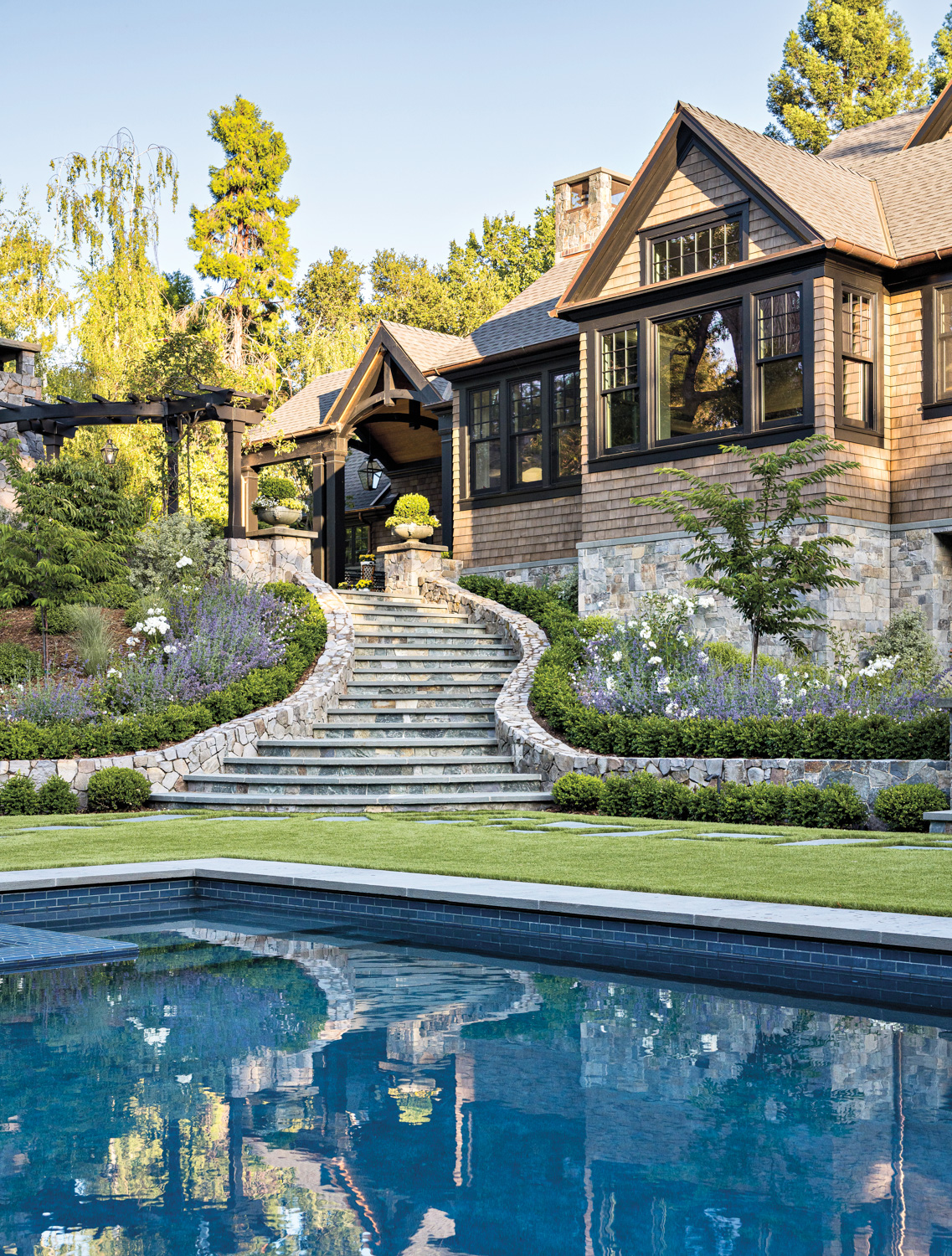 A spacious house with a driveway and lush trees lining the property, creating a welcoming atmosphere.