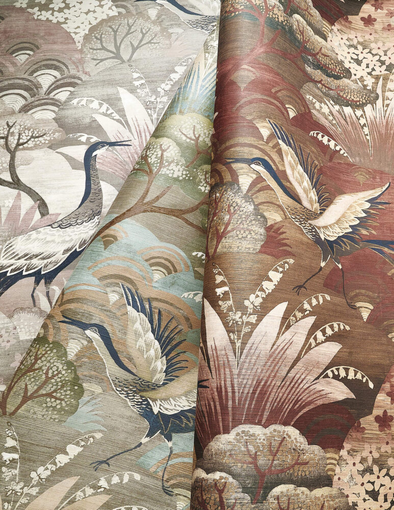 Two pieces of patterned fabric featuring cranes, plants, and stylized clouds in muted tones on the left and warm tones on the right.