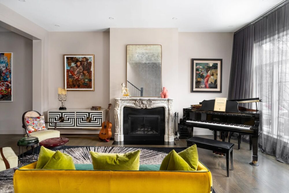 Modern living room with a yellow sofa, fireplace, wall art, a black grand piano, and floor-to-ceiling windows with sheer curtains.