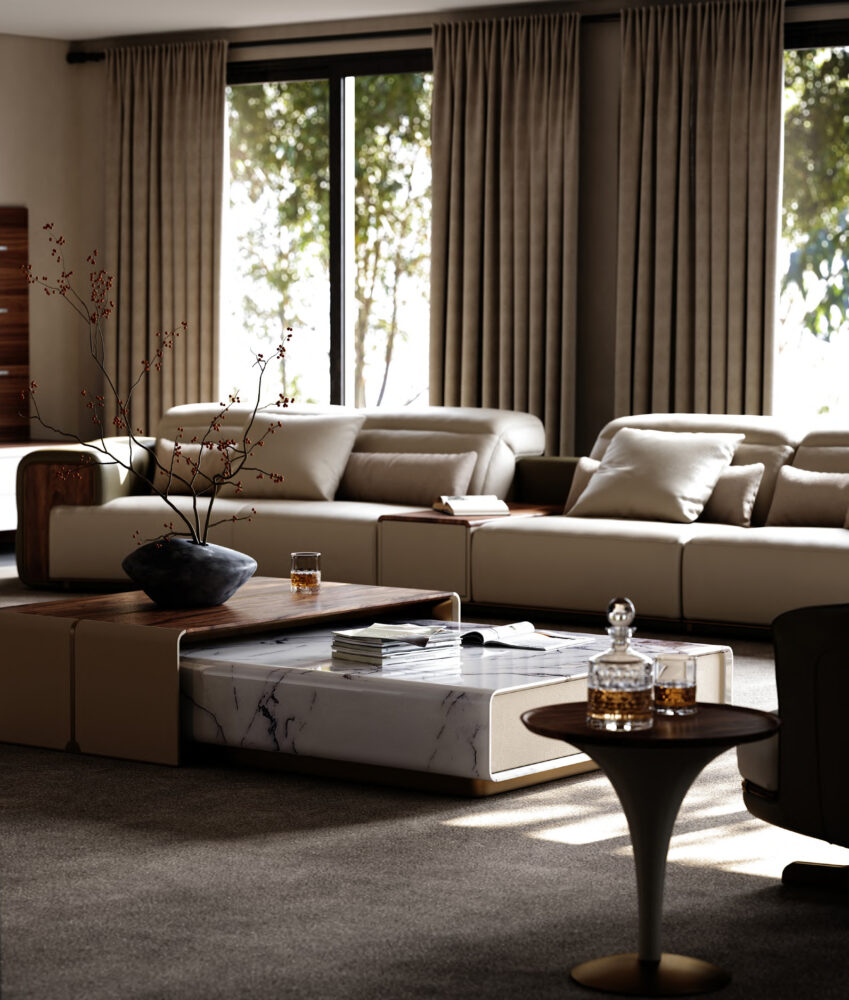 A modern living room with a sectional sofa in ivory upholstery with tobacco leather ends, a stone-topped coffee table with books and a vase, and a small pedestal table holding a glass decanter and tumbler.